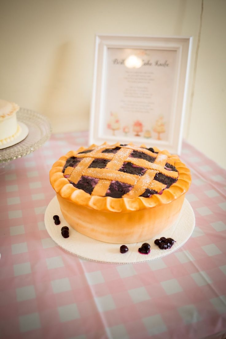 a blueberry pie sitting on top of a table next to a white cake plate