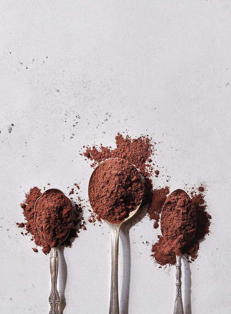 three spoons filled with cocoa powder on top of each other