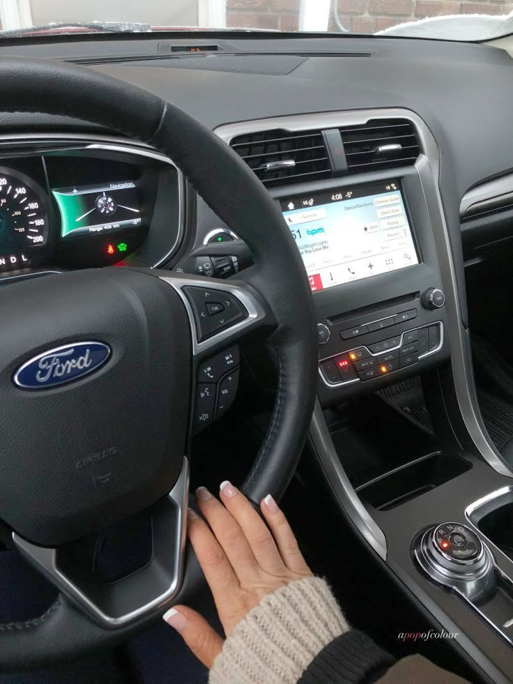 the interior of a ford vehicle with an electronic display and steering wheel, including touchscreens