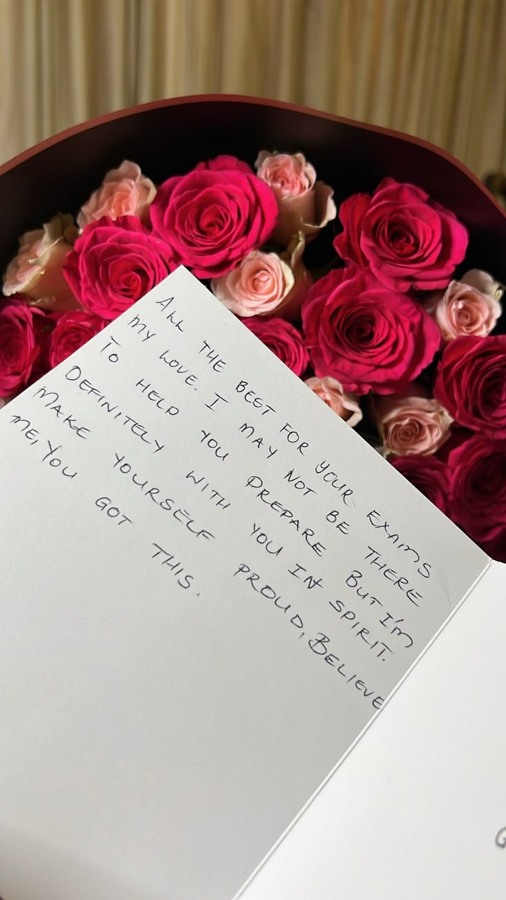 a bouquet of pink roses and a note sitting on top of a table