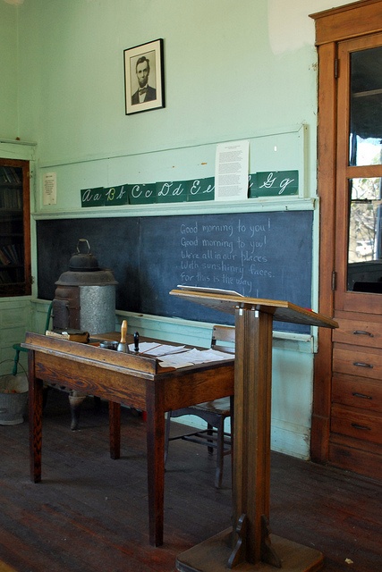 an old fashioned desk in the middle of a room with chalkboard on the wall