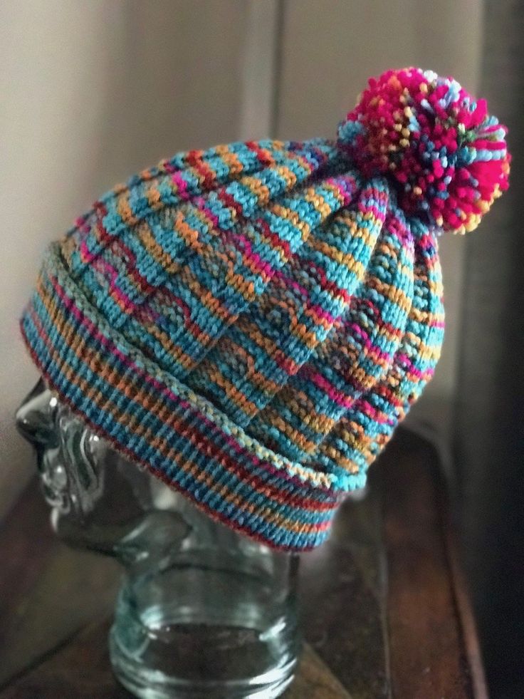 a knitted hat on top of a glass head