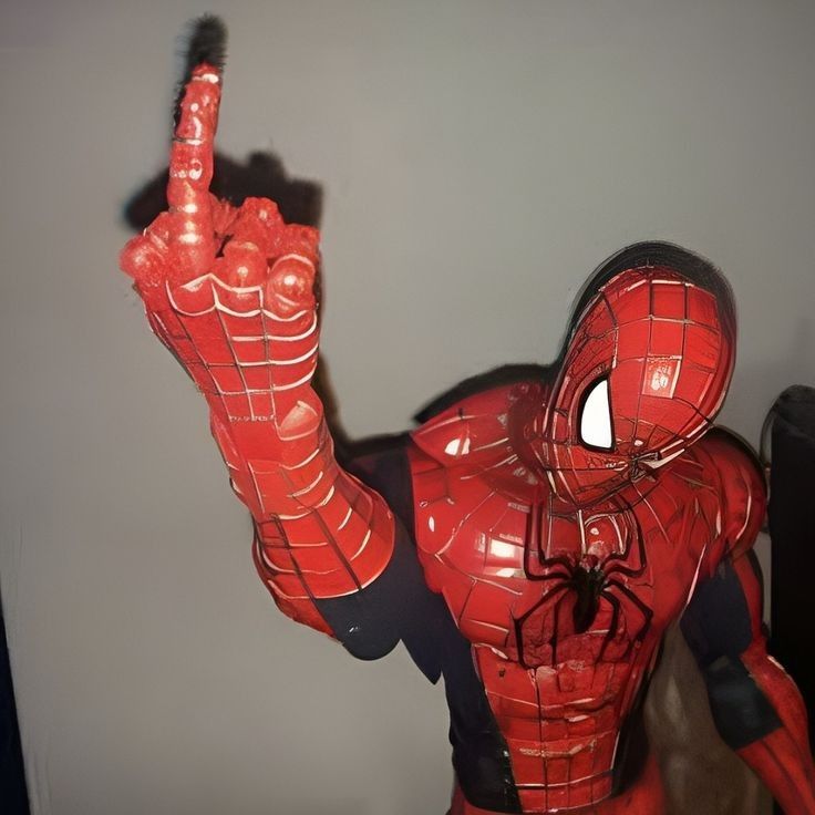 there is a spider man statue on display in the room with it's hands up