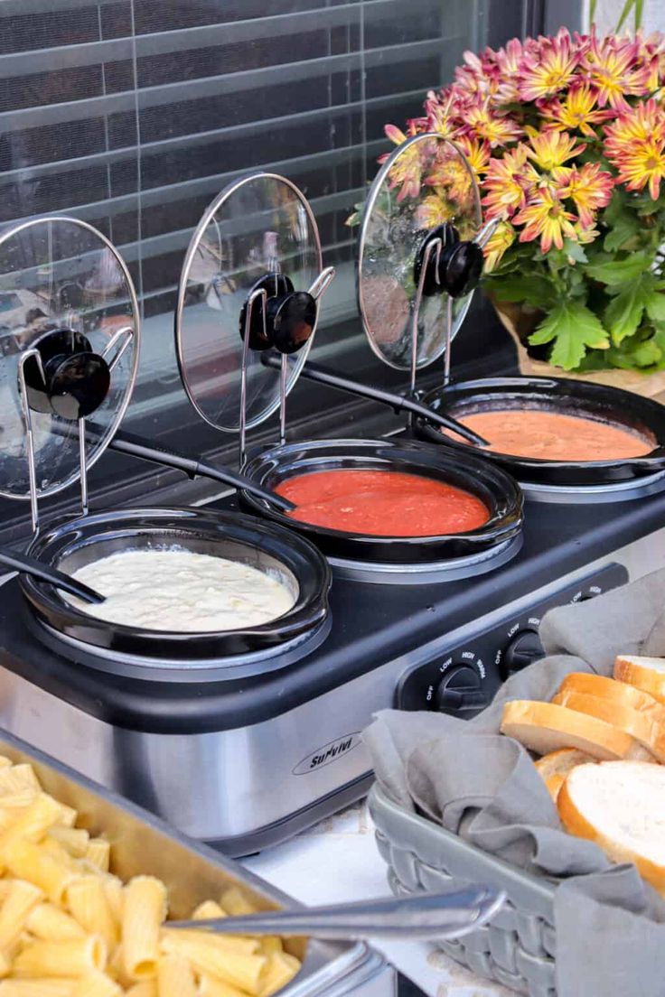 an assortment of different types of food in trays on a buffet table with flowers