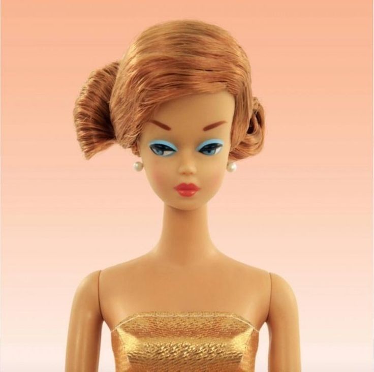 a doll wearing a gold dress with blue eyes and hair in the shape of a woman's head