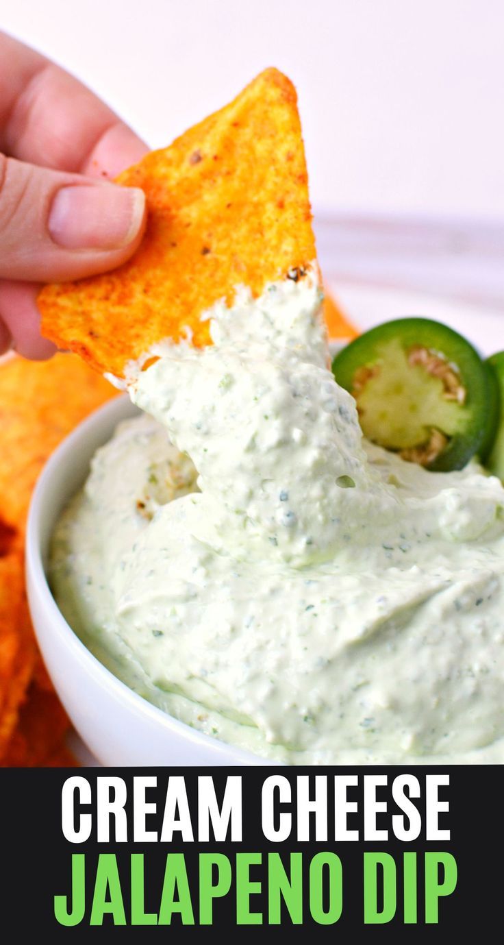 a hand dipping a chip into a bowl of cream cheese jalapeno dip