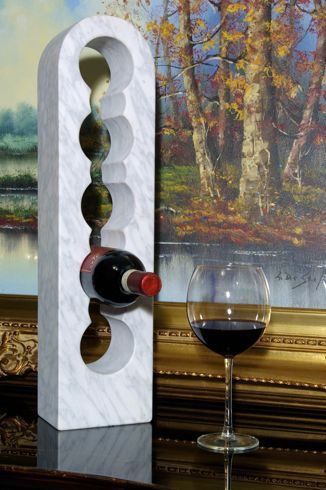 a wine bottle and glass sitting on a table next to a painting with trees in the background