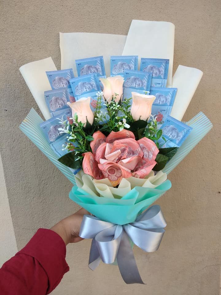 a bouquet of flowers is being held by someone's hand with blue and white ribbons