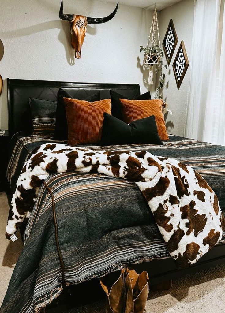 a cow print bed spread and pillows in a bedroom with deer head on the wall