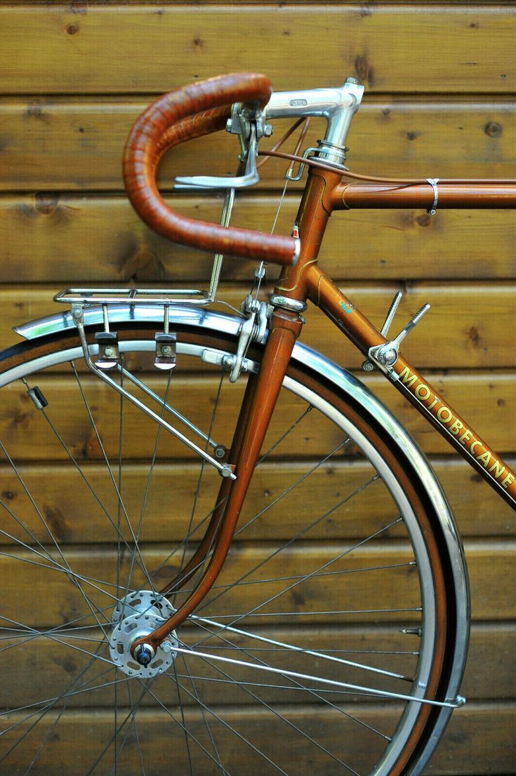 an old fashioned bicycle parked in front of a wooden wall