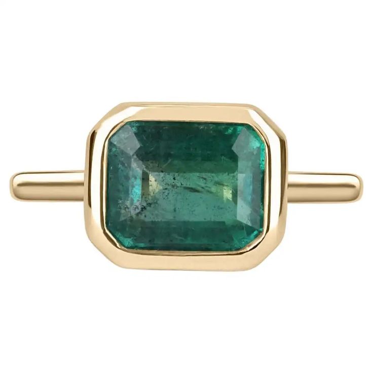 For Sale on 1stDibs - Displayed is a vibrant-green emerald, solitaire, emerald-cut bezel ring in 14K yellow gold. This gorgeous solitaire ring carries a full 3.85-carat emerald Emerald Cut Emerald Ring, Stone Gold Ring, Engagement Ring Emerald Cut, Bezel Set Engagement Ring, Emerald Cut Ring, Engagement Ring Emerald, Ring Emerald Cut, Bezel Engagement Ring, Trilogy Ring