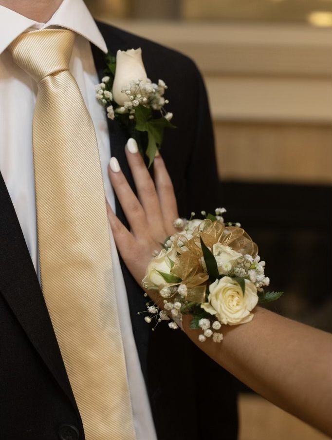 a close up of two people wearing boutonnieres with flowers on their hands