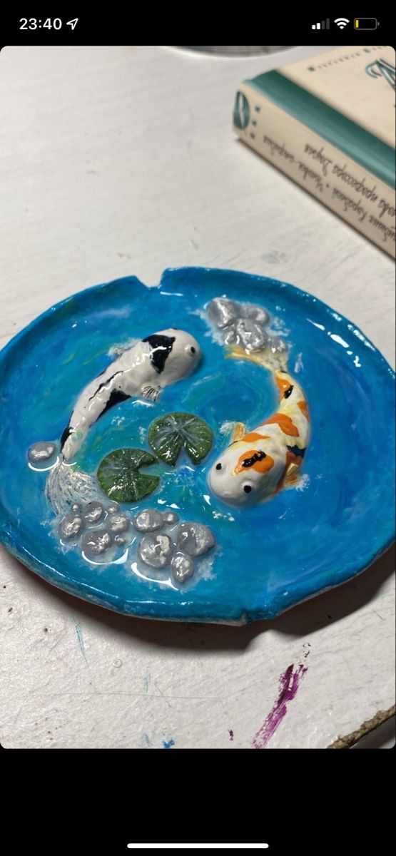 two koi fish swimming in a blue plate with bubbles on the bottom and water around it