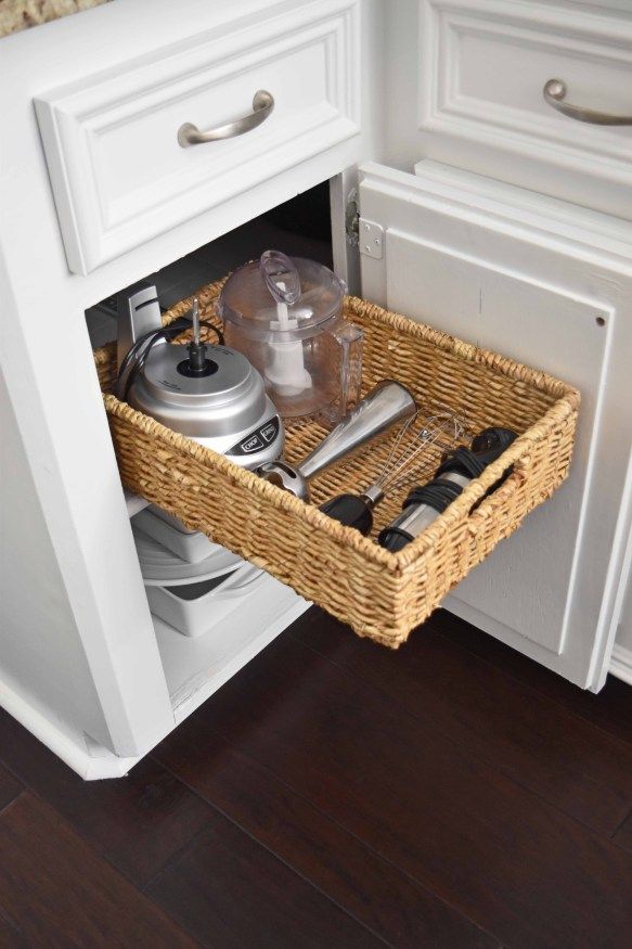 an open cabinet with utensils and other kitchen items in the bottom drawer area