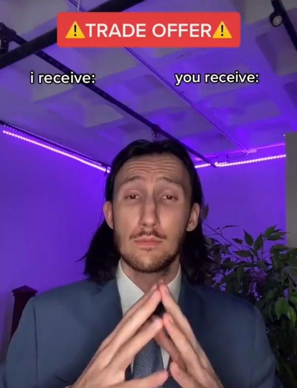 a man in a suit and tie is making a gesture with his hands while standing under a sign that reads trade offer i receive you receive