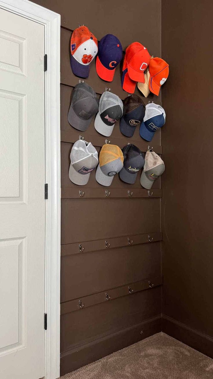 baseball caps are hanging on the wall in front of a white door and brown walls