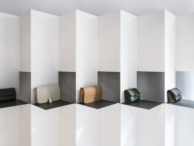 a row of white shelves with purses on them