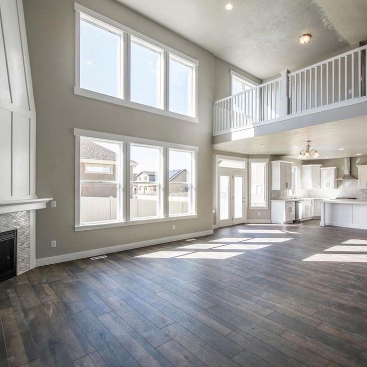 an empty living room with wood flooring and white railings on the second story