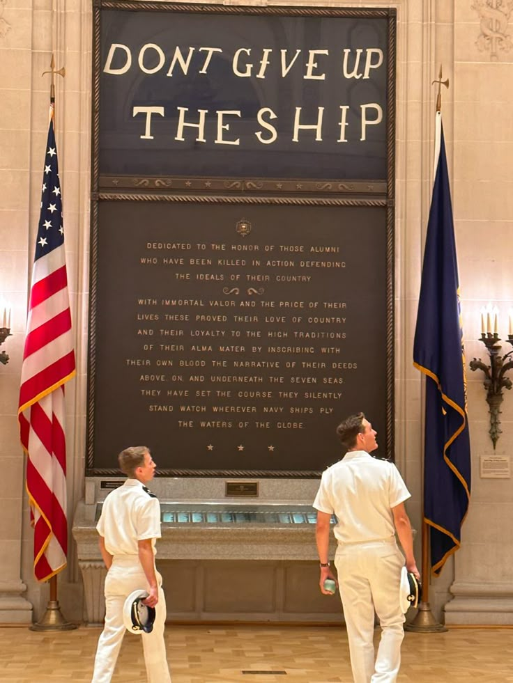 two men standing in front of a sign that says don't give up the ship