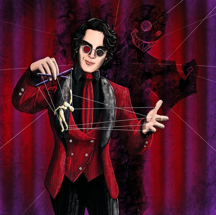 a man in a red suit and black tie holding strings with his hands while standing next to a purple curtain