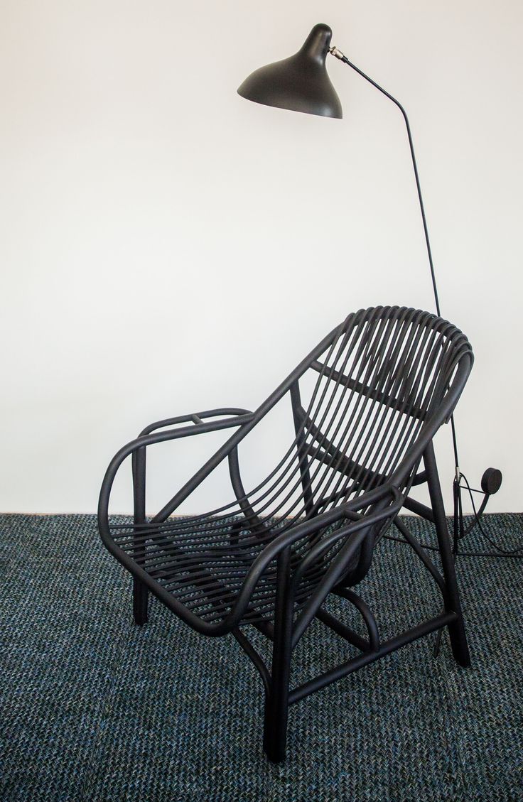 a chair with a lamp on top of it in front of a wall and carpet