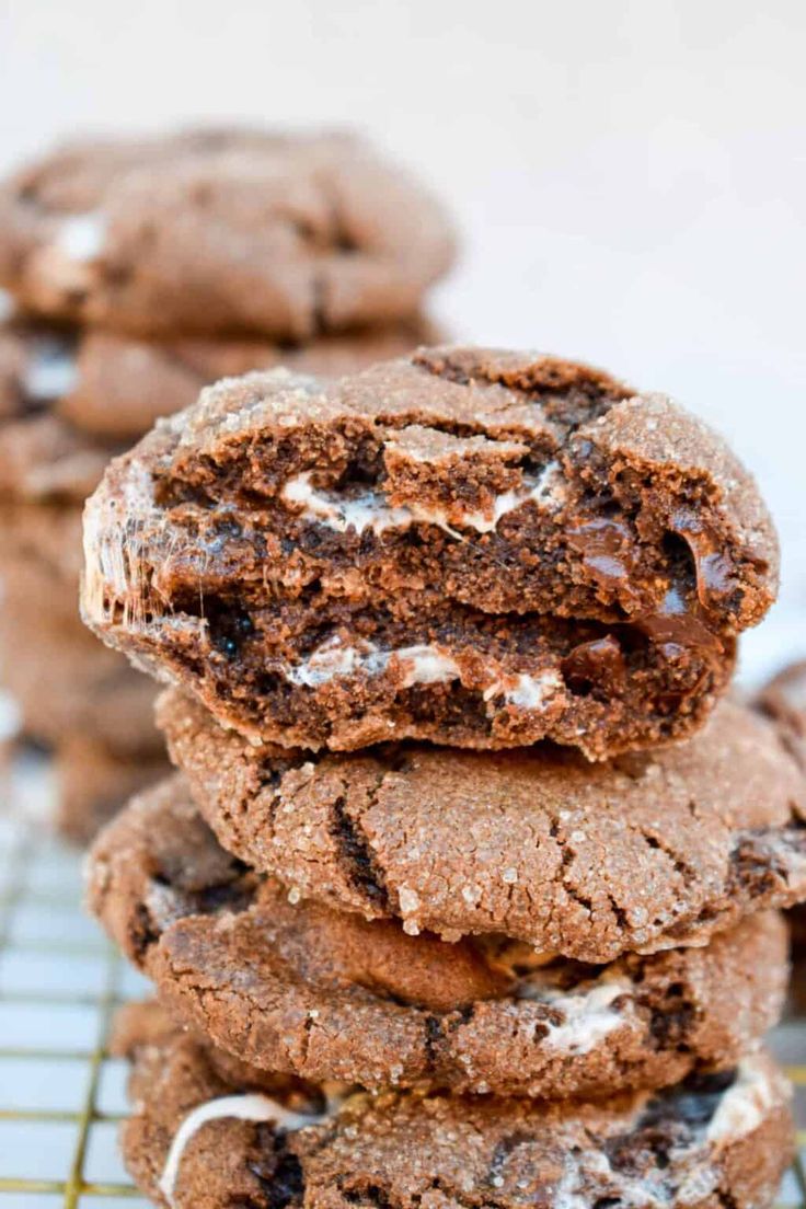 chocolate cookies with white frosting stacked on top of each other in front of a cooling rack