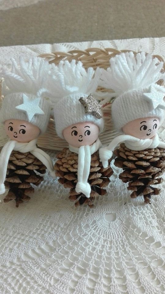 three small pine cones with white knitted hats on them and one is holding two people