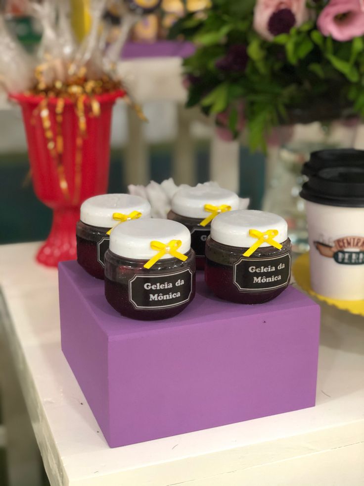 three jars of jam sitting on top of a purple box next to a cup of coffee