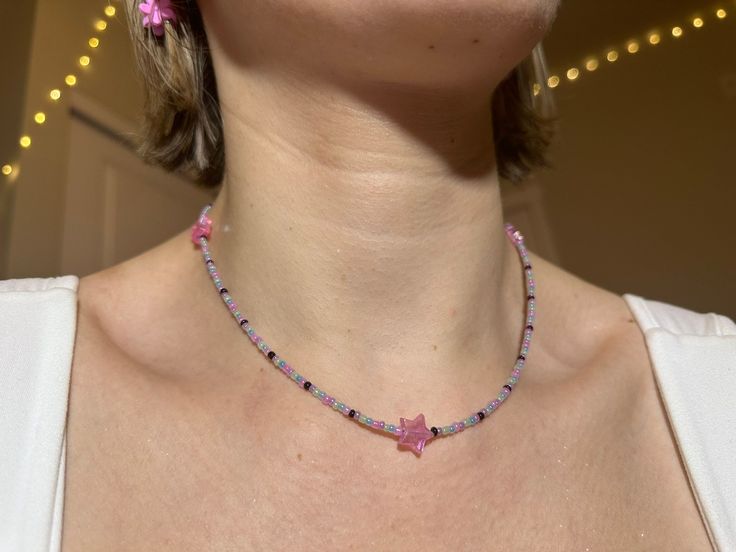 "dainty y2k-inspired necklace featuring pastel & black glass beads with acrylic pink holographic stars. two lobster clasps at the ends make it easy to close. this necklace is approximately 16.5\" in length and hits right around my collarbone." Pink Beaded Necklaces, Trendy Pink Necklace With Star Charm, Pink Star-shaped Jewelry With Colorful Beads, Pink Handmade Star Necklace, Handmade Pink Star Necklace, Diy Bead Necklace Ideas, Necklace Beads Ideas, Beads Necklace Ideas, Pink Beads Necklace