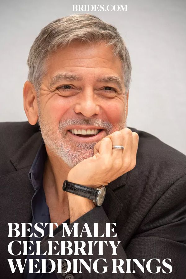 an older man with grey hair and a black blazer smiles at the camera while wearing a watch