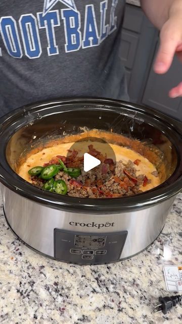 a crock pot filled with meat and vegetables sitting on top of a granite counter