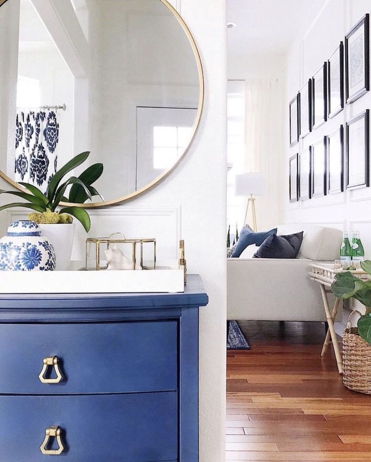 a blue and white dresser with a mirror above it