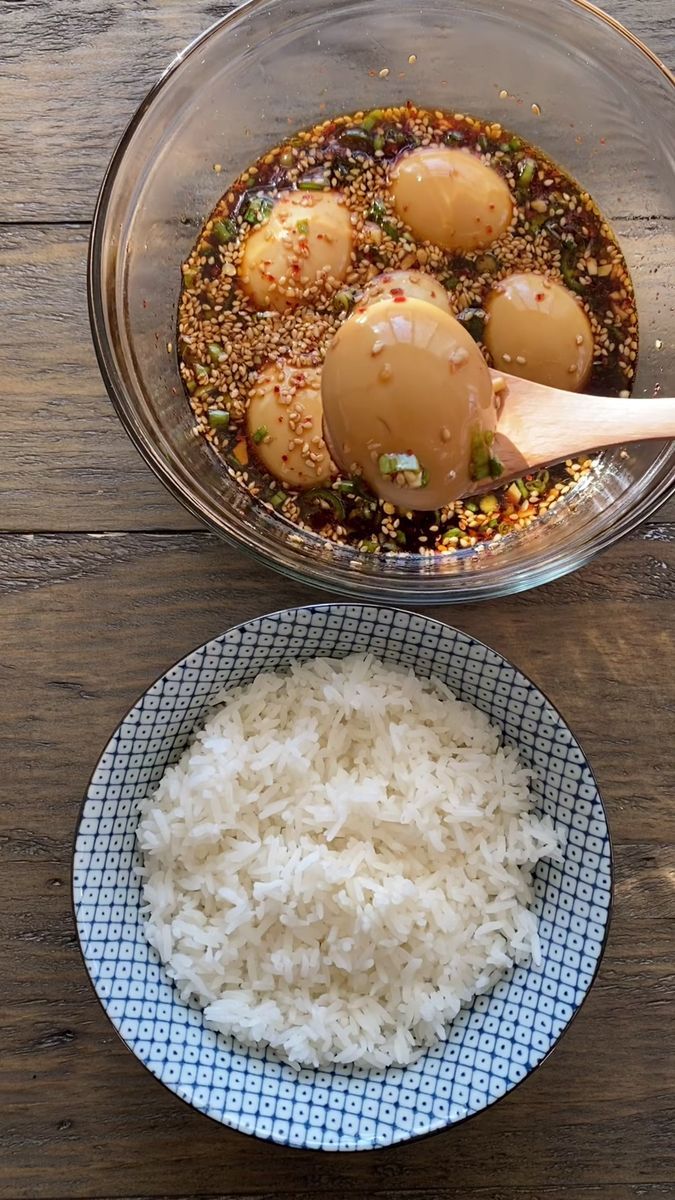 two bowls filled with rice and eggs on top of a wooden table