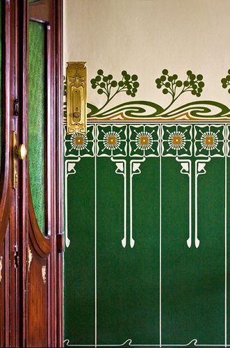 a green and white wall with flowers painted on it's side next to a wooden door