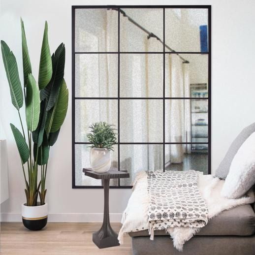 a living room with a couch, mirror and potted plant on the side table