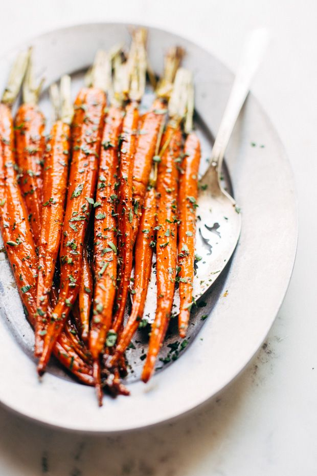 a white plate topped with carrots covered in herbs