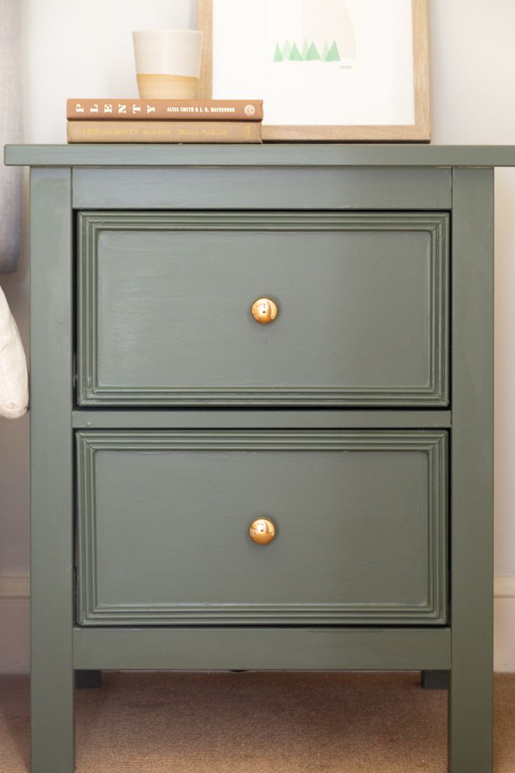 a green nightstand with two drawers and a framed photograph on top of it, next to a bed