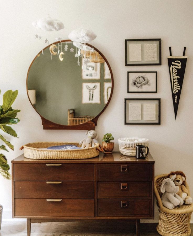 a dresser and mirror in a room with pictures on the wall above it, along with a teddy bear