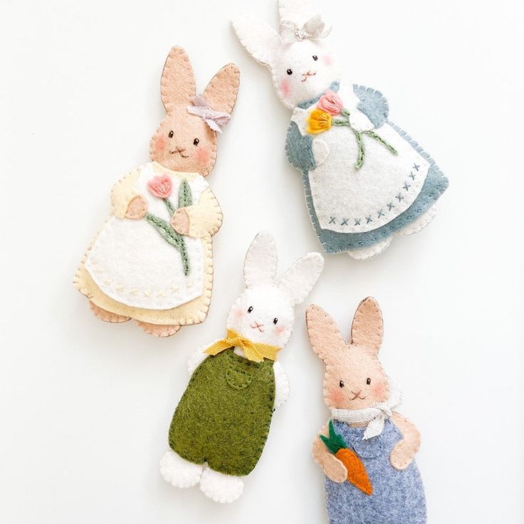 three little felt bunnies are sitting next to each other