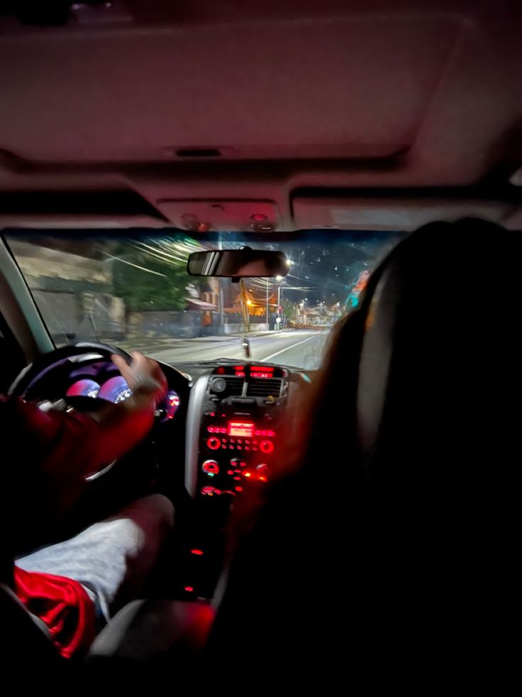 the interior of a car is lit up with red lights and there are people in it