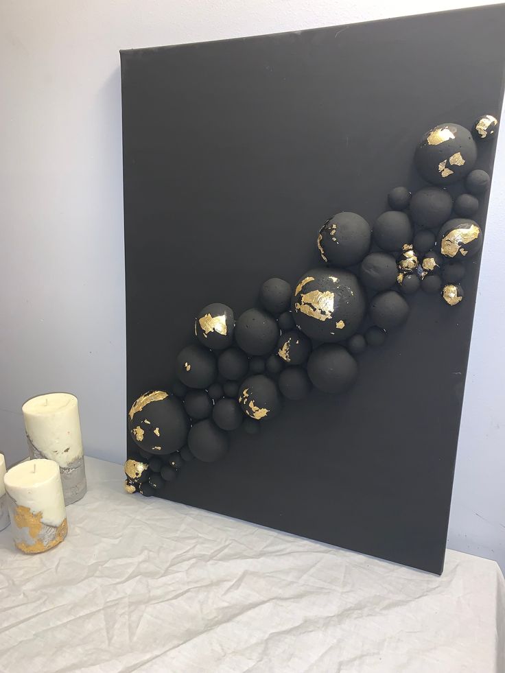 a black and gold painting on display next to candles