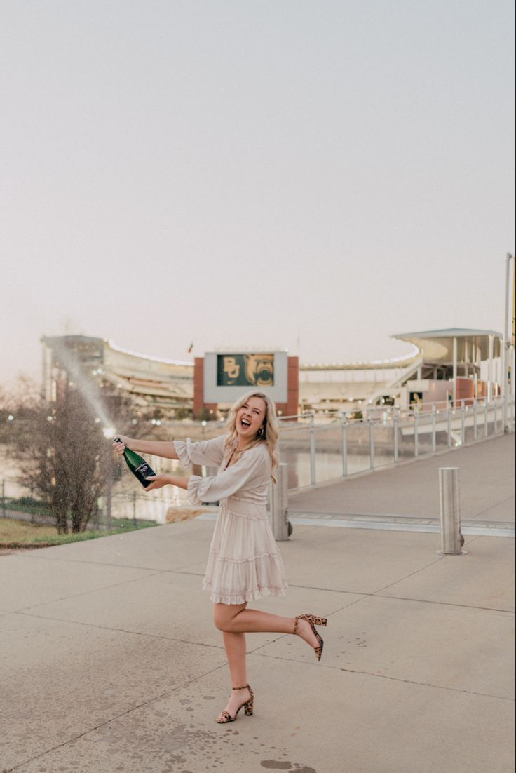 a woman in a white dress is holding a bottle