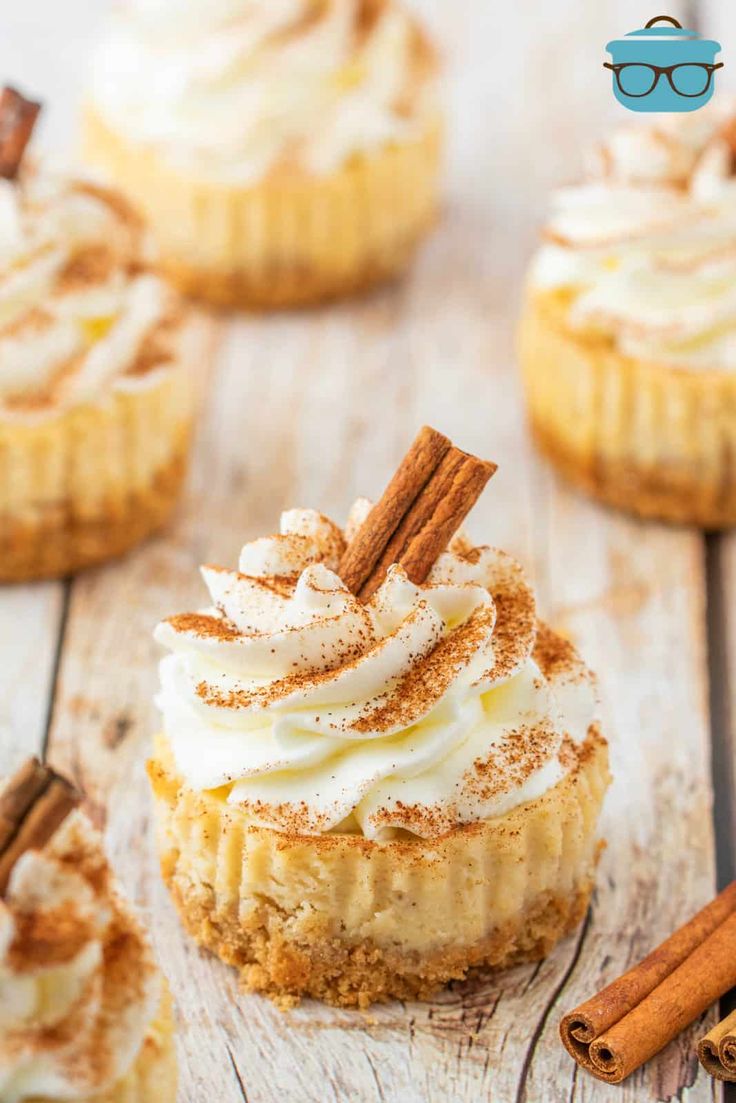 mini pumpkin pies with cinnamon spice toppings on a wooden table next to cinnamon sticks