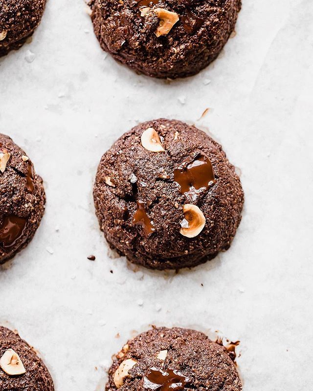 chocolate cookies with peanut butter and sea salt on top, lined up on a sheet of parchment paper