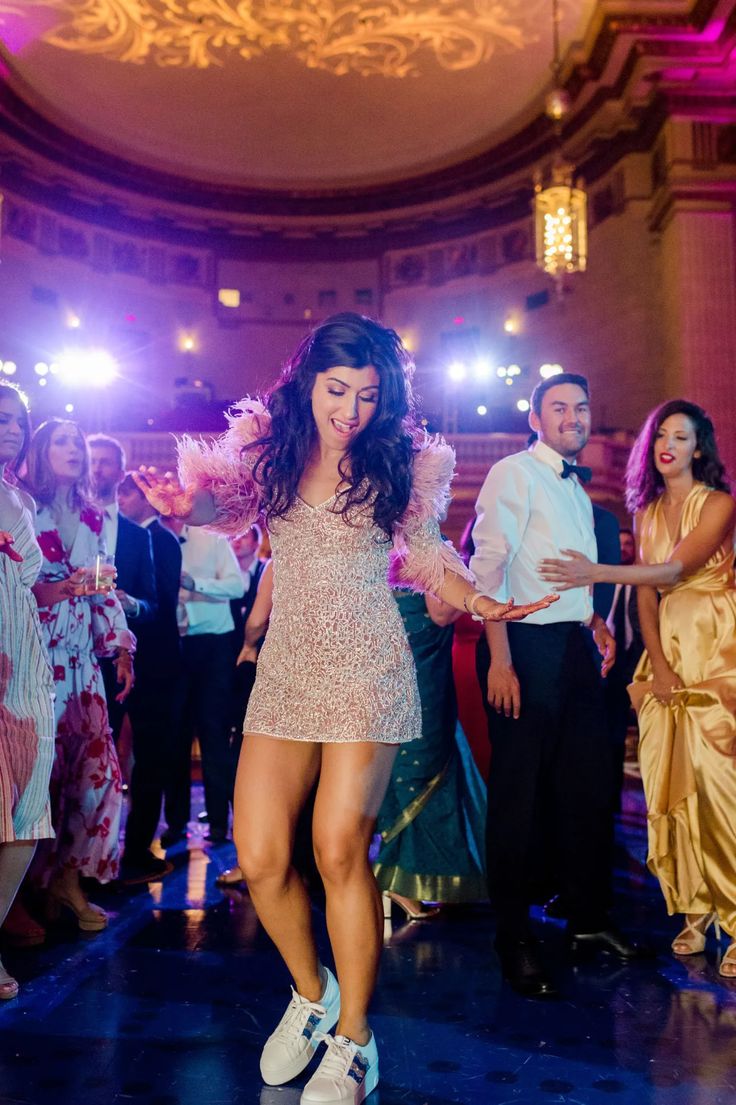 a woman in a short dress is dancing on the dance floor with other people behind her