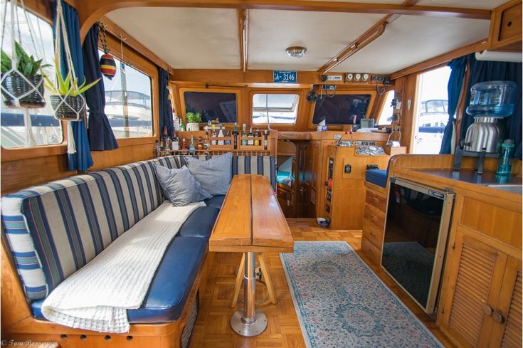 the inside of a boat with wood paneling and blue striped couches on it