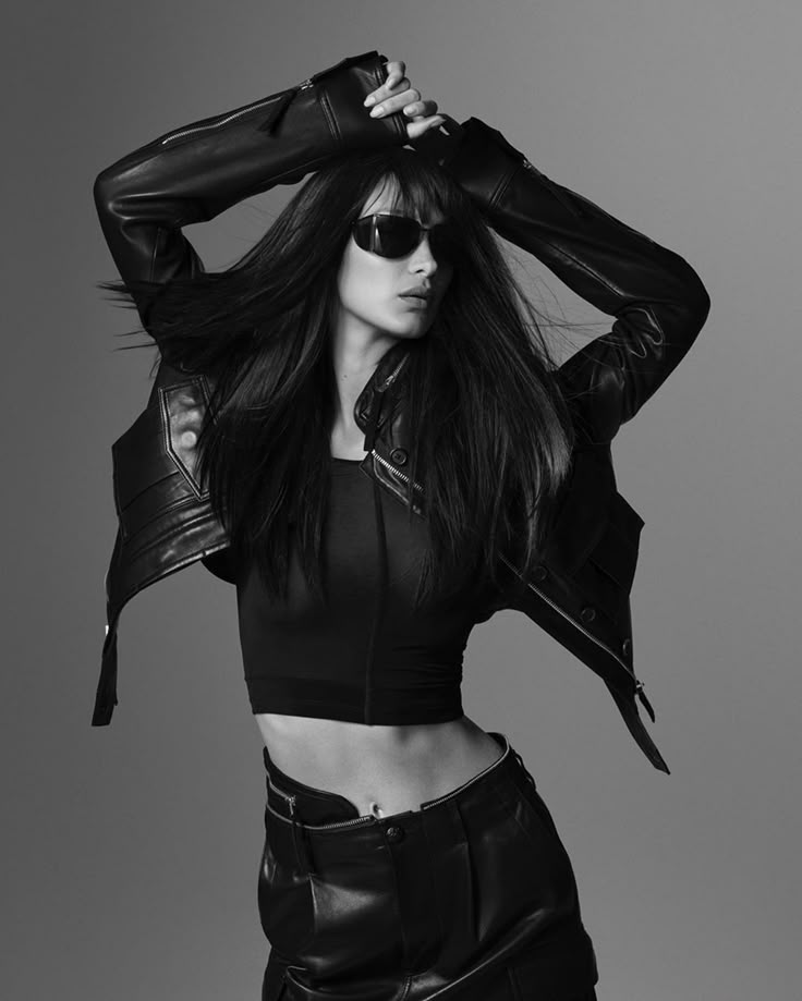 a woman with long hair and leather jacket posing for a magazine cover shoot in black and white