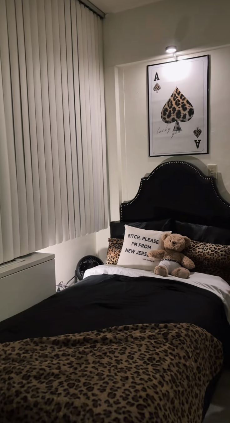 a teddy bear sitting on top of a bed in a bedroom next to a window