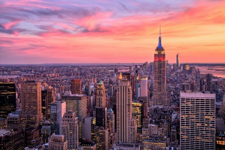 an aerial view of new york city at sunset with the empire building in the foreground