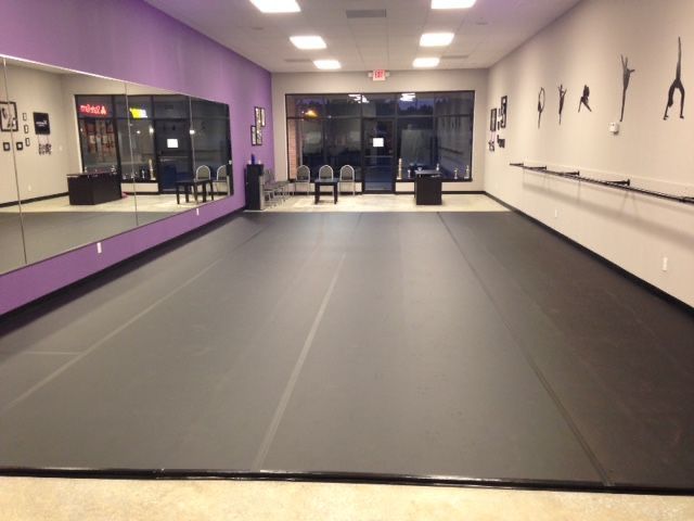 an empty dance studio with mirrors on the wall and purple carpeted floor in front of it